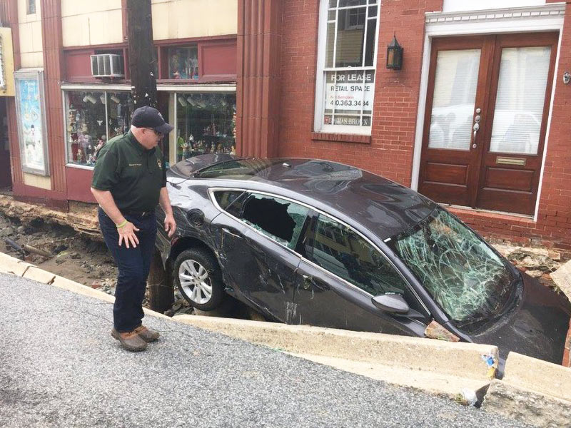 Governor Hogan in front of 8227 Main Street examining car in foundation after July 2016 Flood